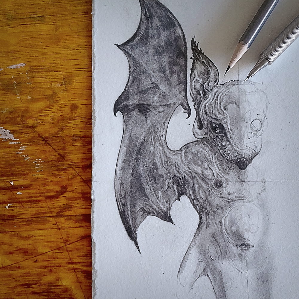Unfinished, graphite only sketch of the left side of the bat's head and wing. A single eye is barely visible in its chest area. A wood pencil and a mechanical pencil are on the sketchpad.